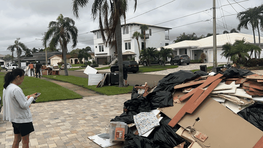 Real job photo: curb and driveway junk pile with bags, wood, and drywall